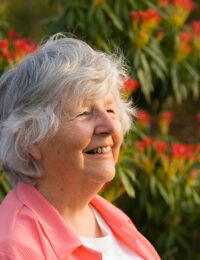 senior woman in front of flowers