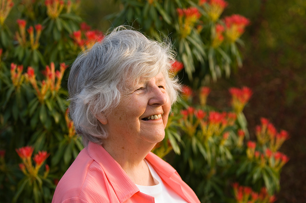 senior woman in front of flowers